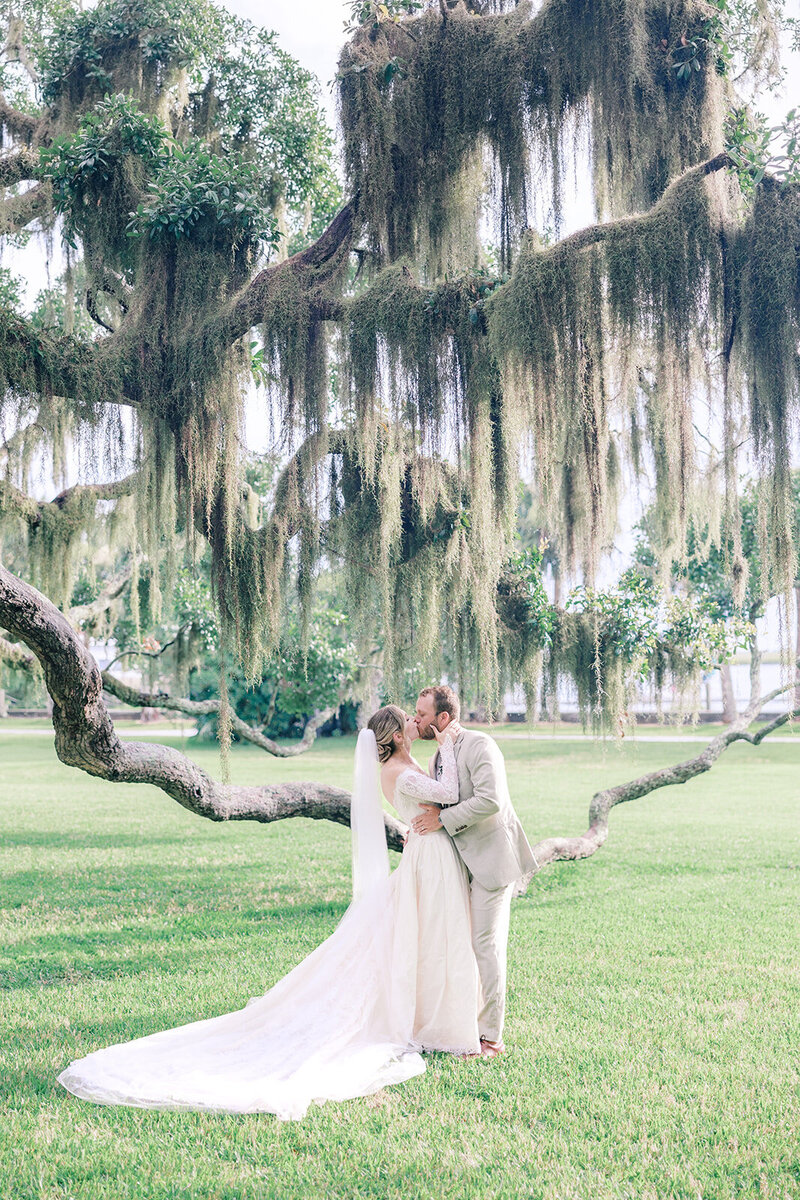 bride and groom kiss under the mossy trees on Jekyll Island Club Resort