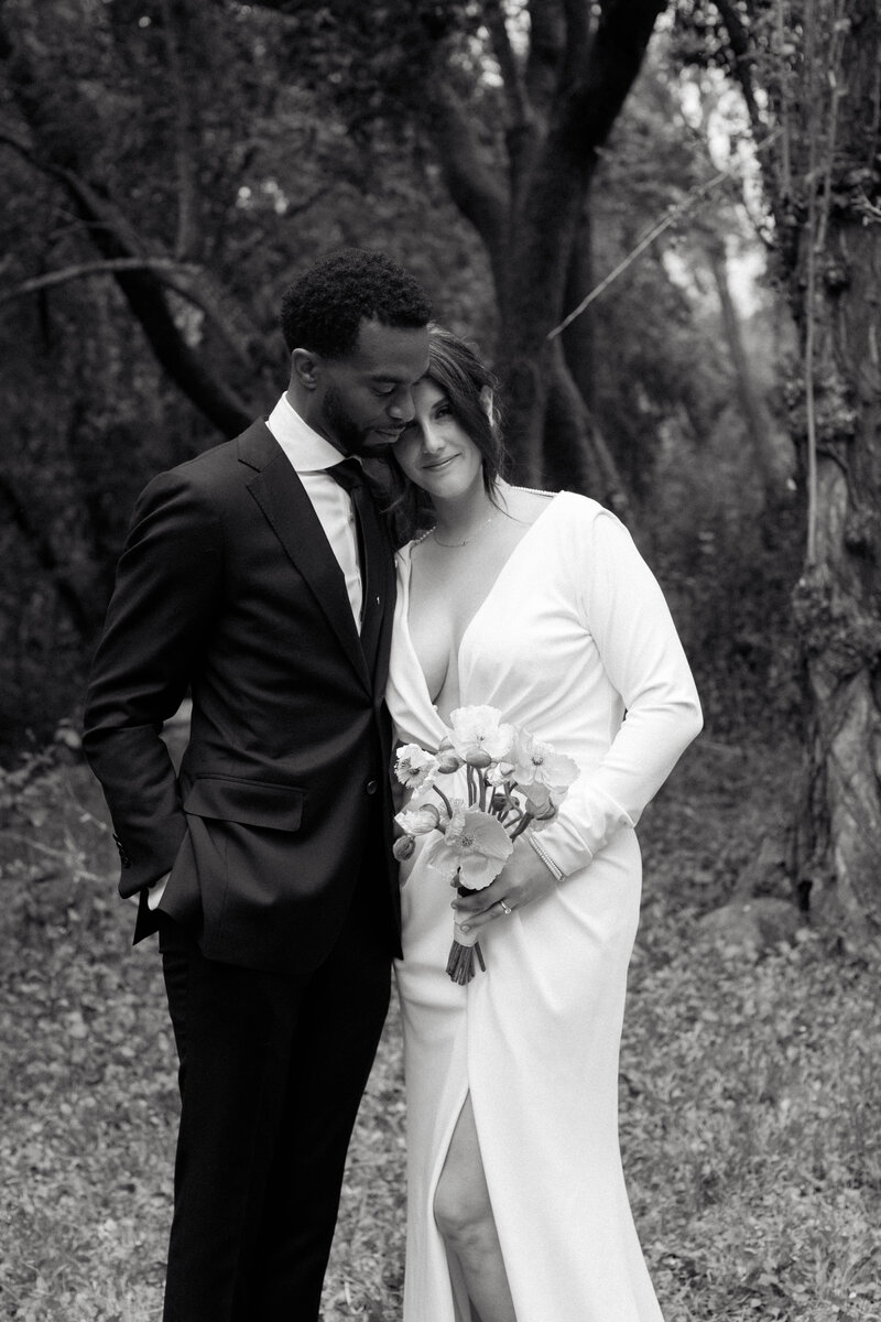 Black and white wedding photography of a bride and groom embracing in nature. Captured by a luxury wedding photographer specializing in timeless, elegant wedding portraits in California and NYC.