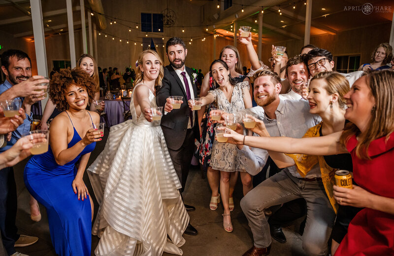 Couple takes shots with their friends at their wedding reception at The Woodlands Barn in Conifer Colorado