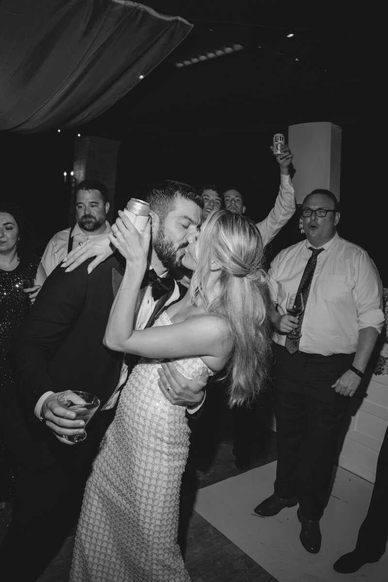 bride and groom kissing on dancefloor while guests cheer