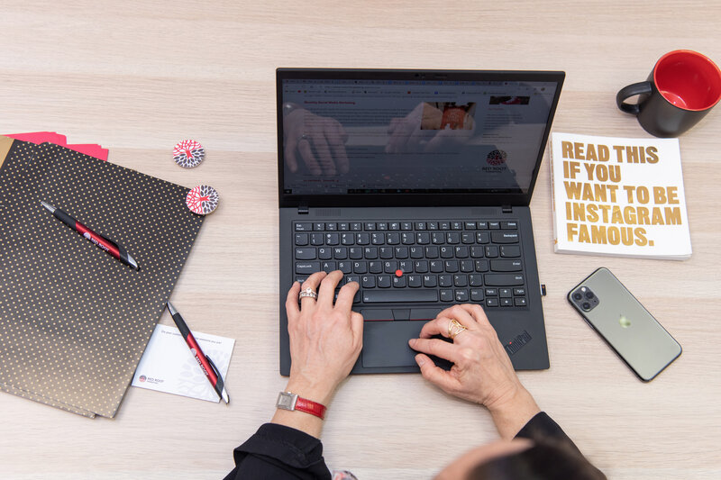 A woman working on her laptop with a book titled 'Read This If You Want to Be Instagram Famous."