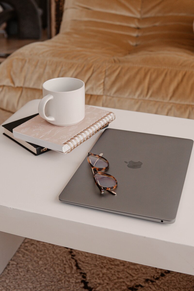 Laptop, notebook, glasses, and coffee mug on a table