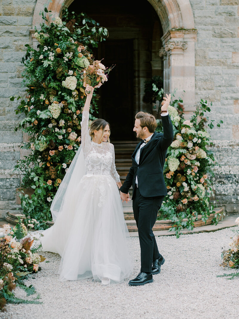 A-bride-and-groom-waving-at-each-other-in-front-of-a-castle