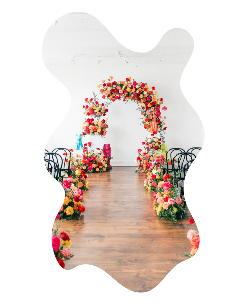 Dramatic arched floral installation with bold colors and movement, perfect for modern wedding receptions in the Dallas area.