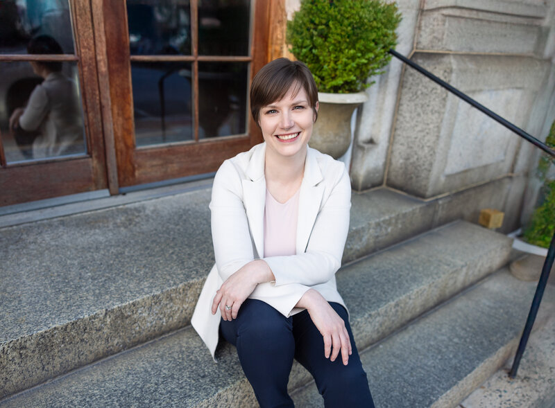 A-business-woman-smiles-during-her-lifestyle-headshots-in-Baltimore-Maryland-while-sitting-on-steps