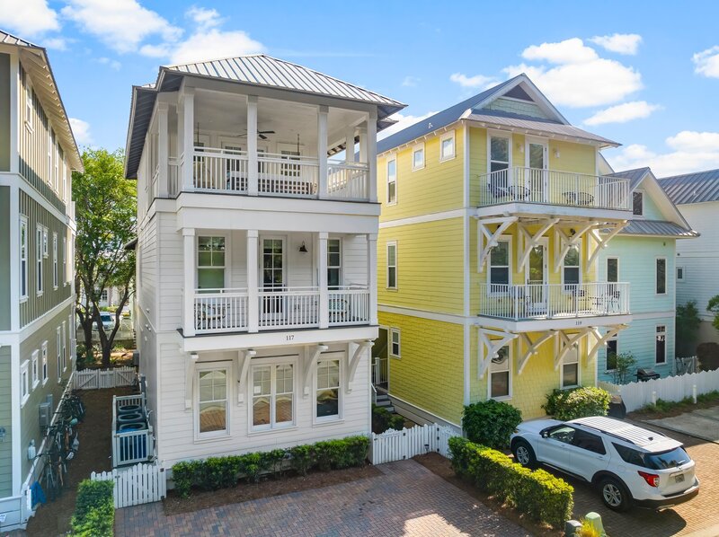 Three-story white beach house with balconies, located in Carillon Beach near Santa Rosa Beach and Alys Beach.