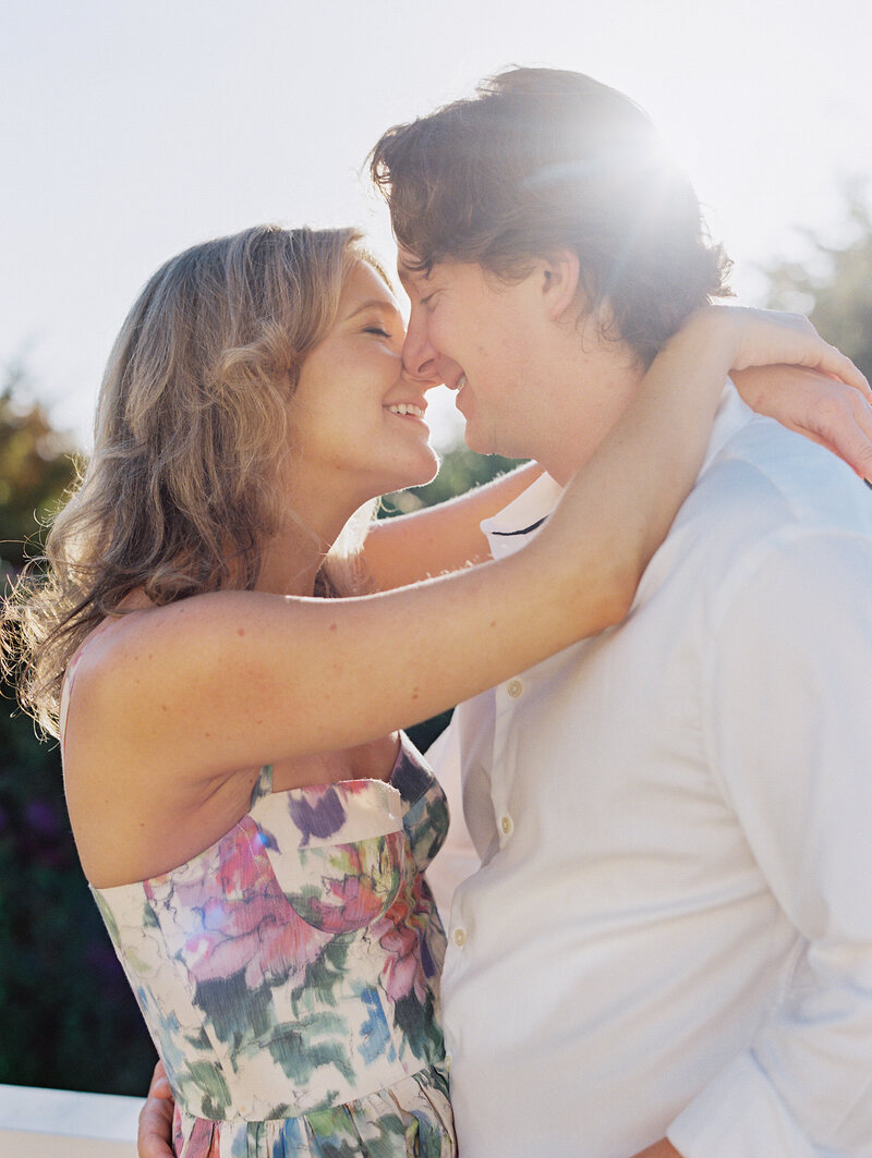 bride wearing a white tailored pant suit for engagmeent session and red lipstick with hair pulled back in a chic pony