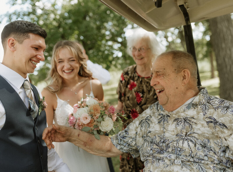 Bride and groom laughing and holding hands with their grandparents after the ceremony, captured in a candid, heartwarming moment by Rainstorm Photo & Video.