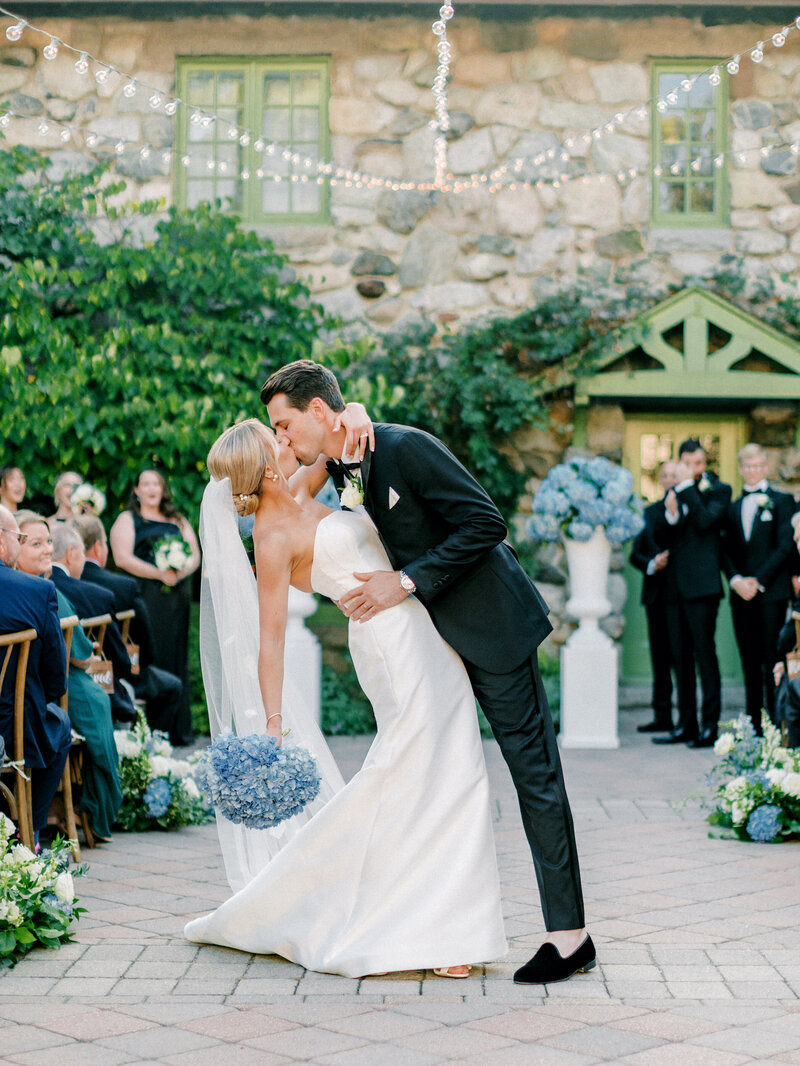 Bride and groom dip kiss as they recess down the aisle