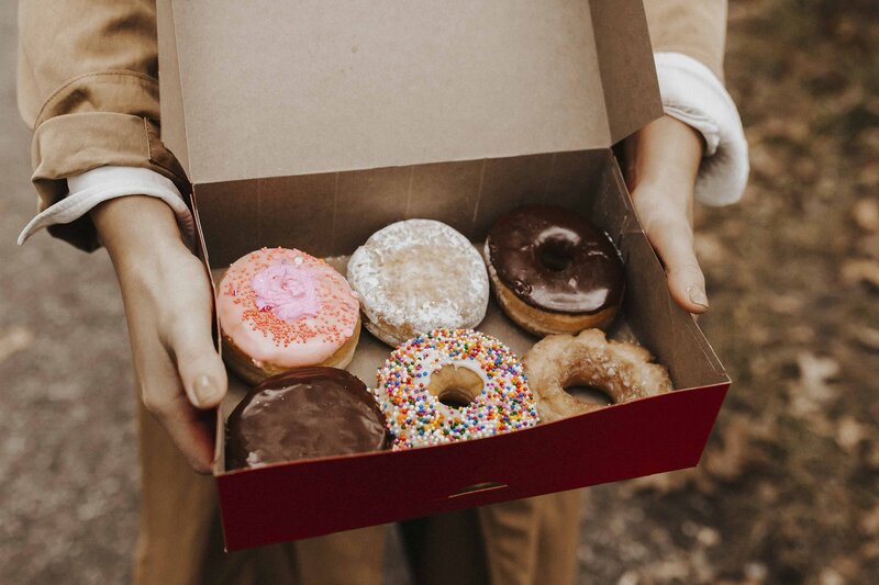 Sarah holds an opened variety box of full-size donuts from Tim Hortons. 