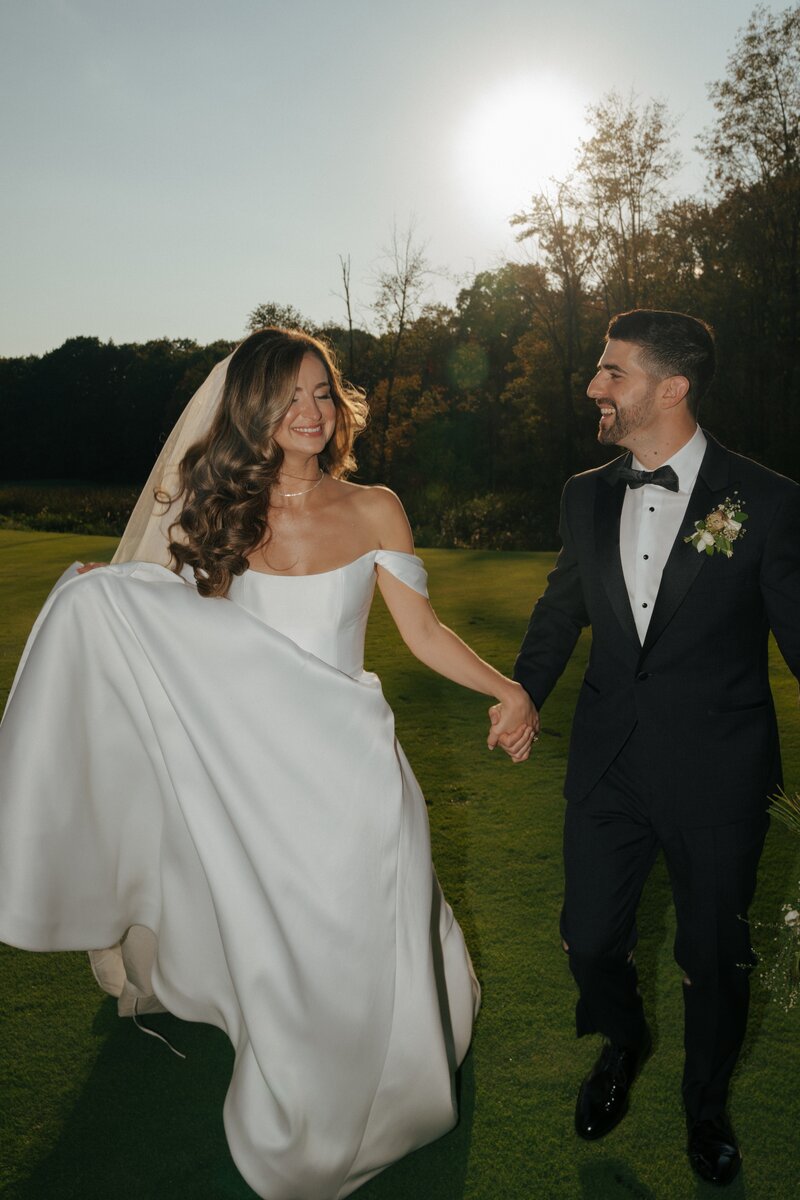 bride and groom running playfully and laughing