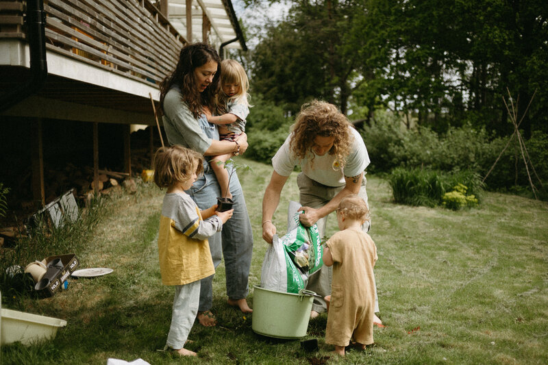 En familj planterar i trädgården under en familjefotografering