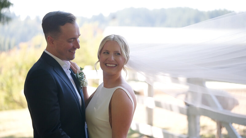 groom smiling at bride while bride smiles at the camera