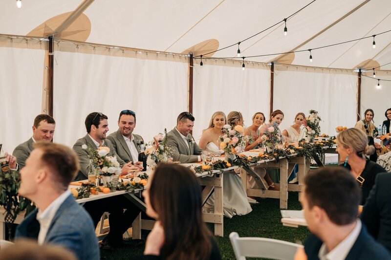 bridal party sitting at wedding reception in stretch tents and tipis in southland at the farm chapel