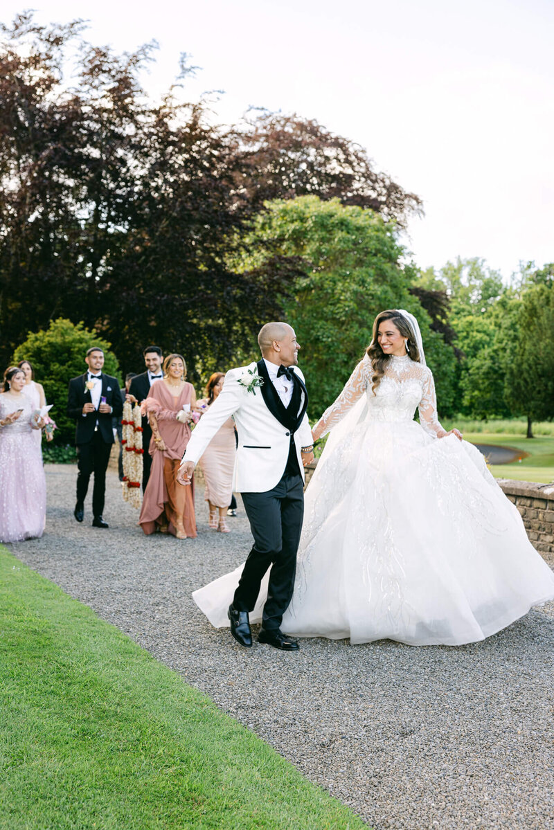 A wedding photo showing the married couple walking hand in hand smiling after their ceremony at Luttrellstown Castle in Dublin Ireland