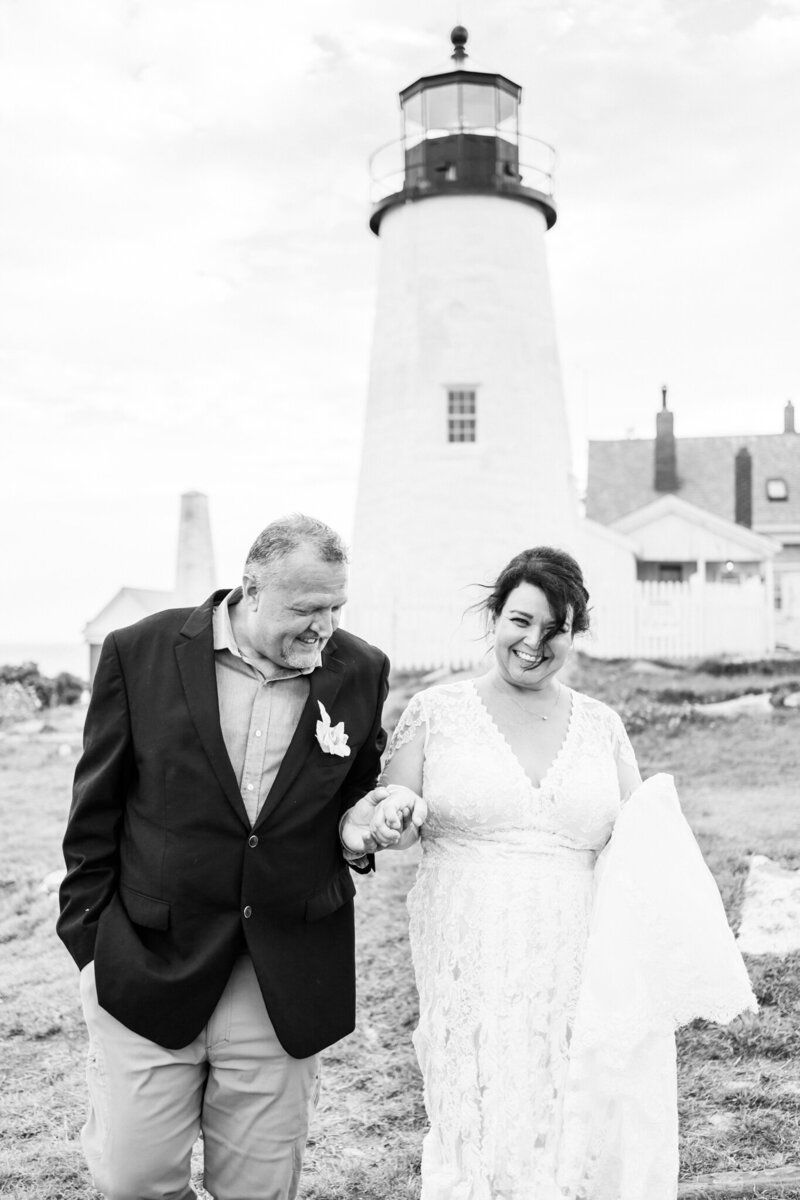 Black and white image of a couple walking in front of a Maine Lighthouse | Maine elopement photographer | Adventure and Vows