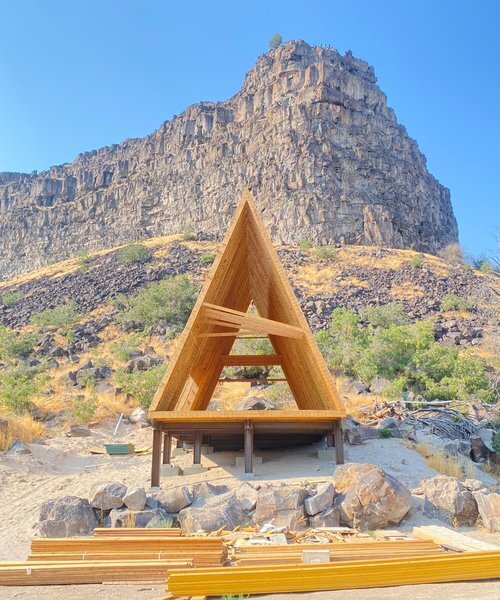 A-frame Raw framing structure of The Perrine Hideaway, with exposed wooden beams and a rugged canyon backdrop
