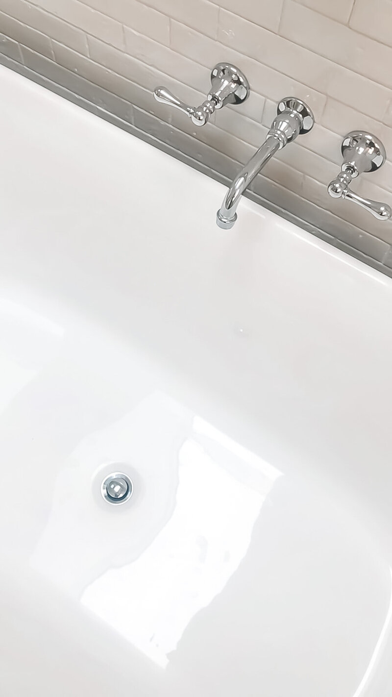 A clean white bathtub with chrome faucet handles and a drain, epitomizing luxury home design Newcastle residents adore.