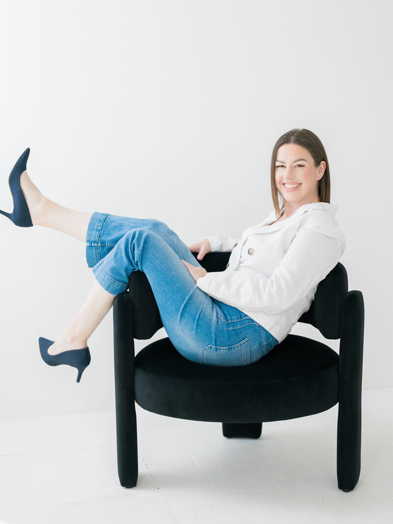 Sara Wright, owner and lead planner of Wander Event Co., seated in a modern black chair during a bright, minimalist brand photoshoot.