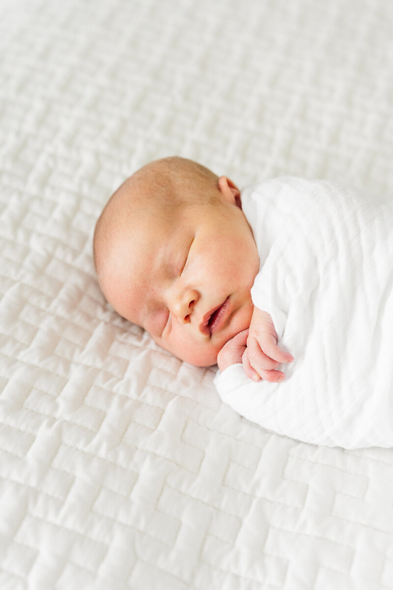 Sleeping newborn baby swaddled in soft fabric, lying peacefully on their side with a calm expression