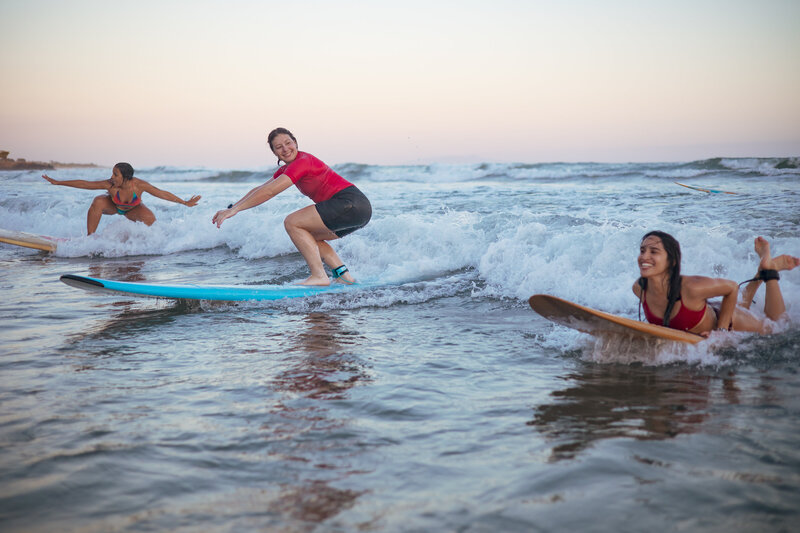 Three surfers ride wave during surf retreat