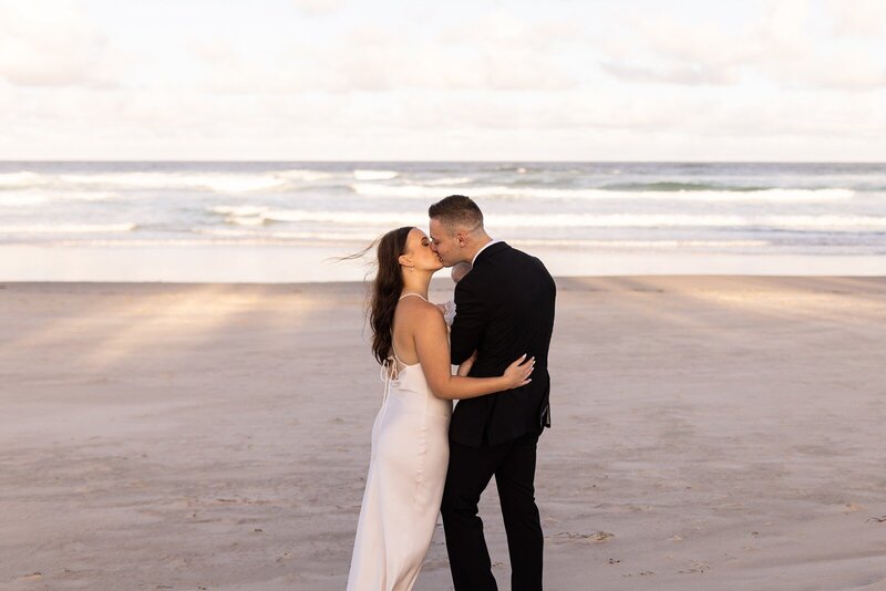 A bride and a groom kissing on the beach
