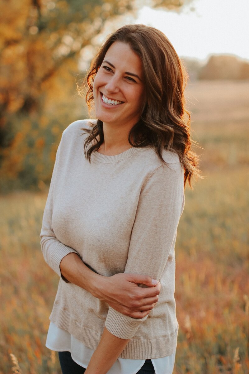 A smiling woman stands in a field representing Grounded Nutrition Therapy in Littleton, Colorado.