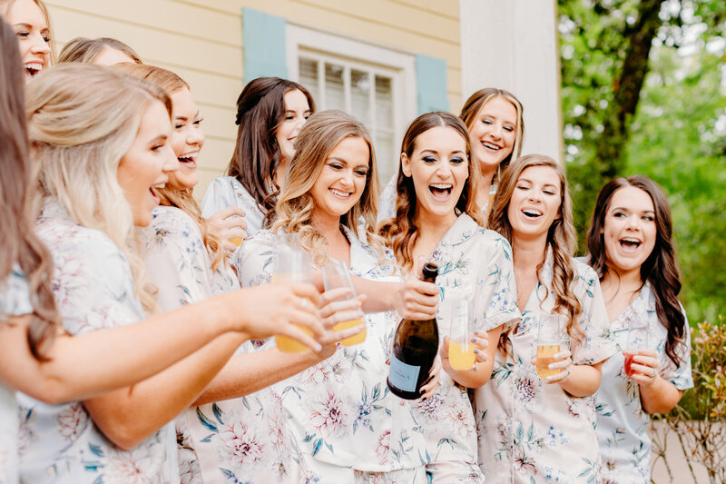 Bridesmaids and bride popping champange at Belhaven home before wedding in Jackson, MS.