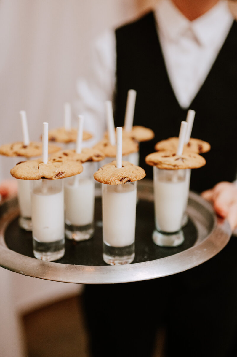Catering tray of cookies and milk being passed amongst guests