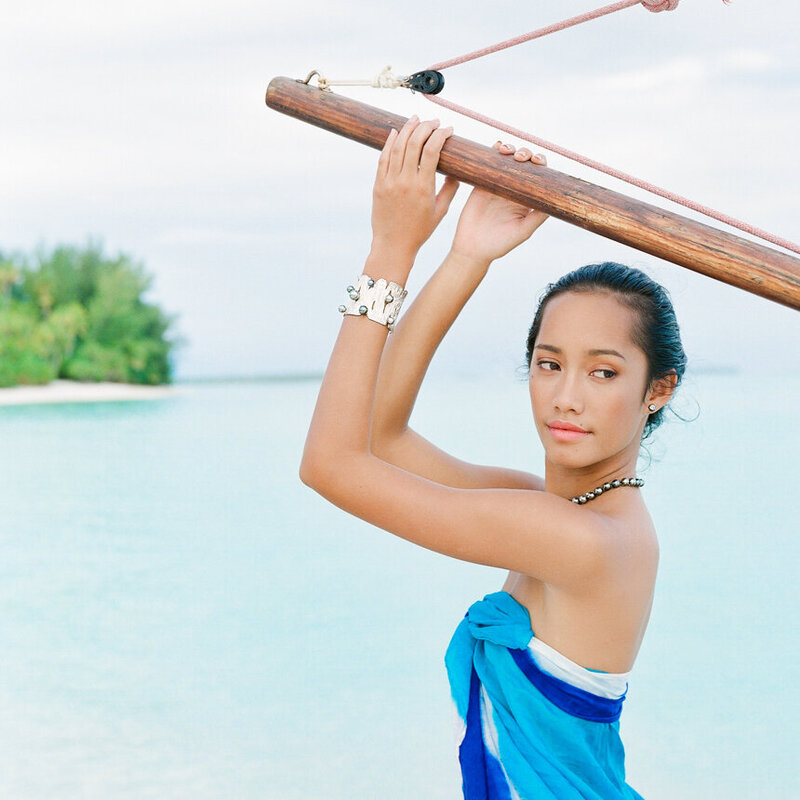 Close portrait Vahine woman from Tahiti with beautiful tahitian pearls and her boat, the beach in the background