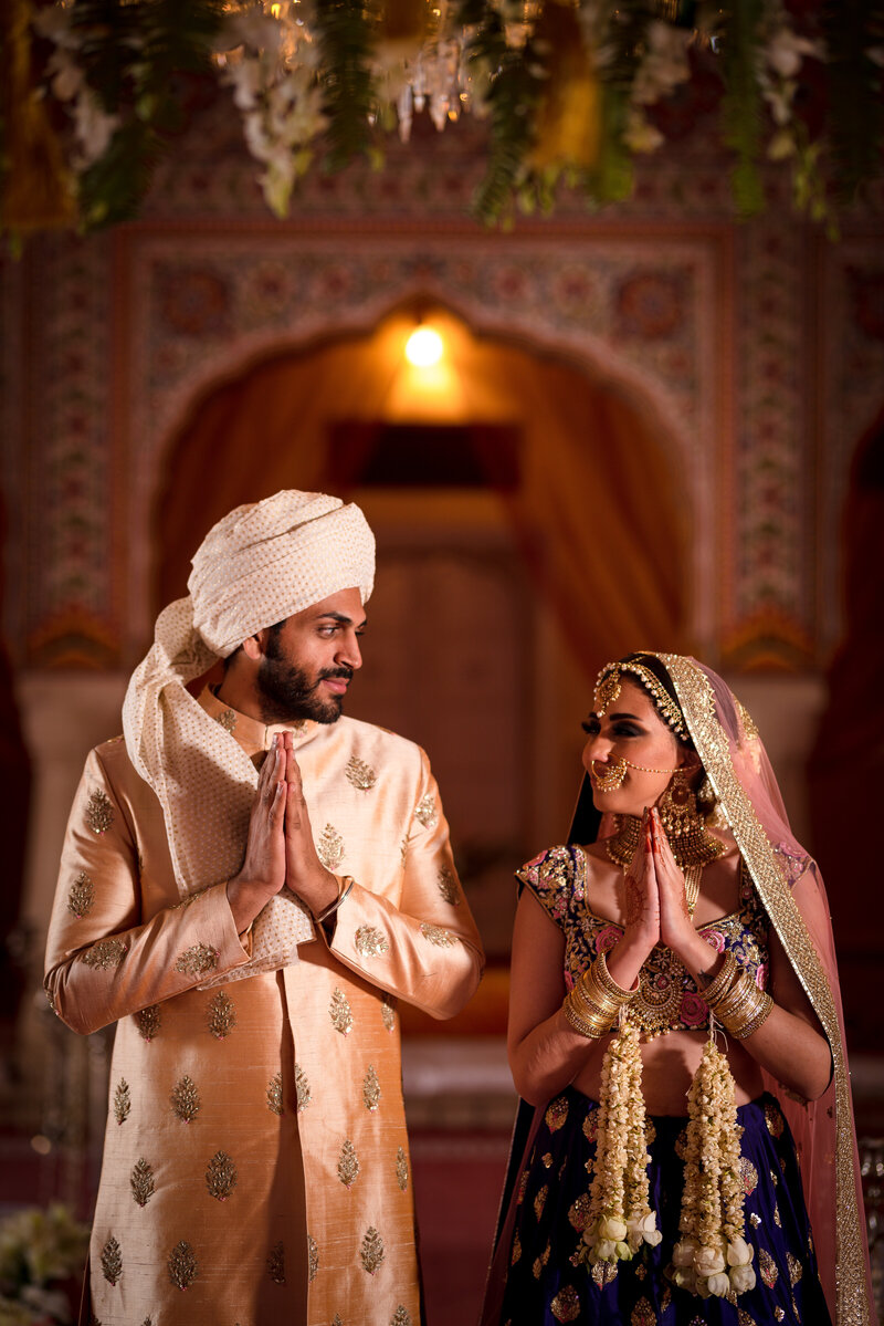 sikh couple holding hands in white and red attire while smiling