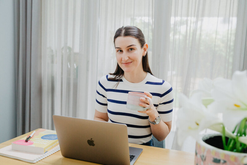 Nutritionist drinking tea inside with laptop