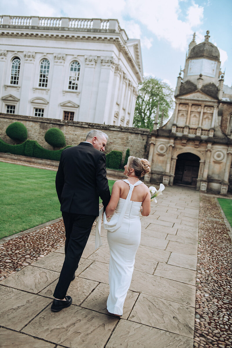 Tilted fashionable portrait of a couple exploring their luxury wedding venue. The bride holds lilies and is wearing a vivienne westwood dress.