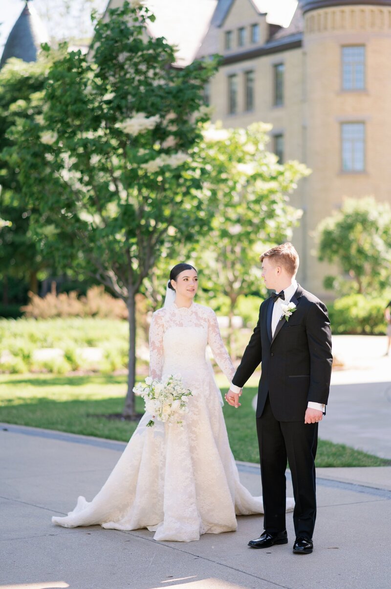 bride and groom walking on Notre Dame's campus while holding hands