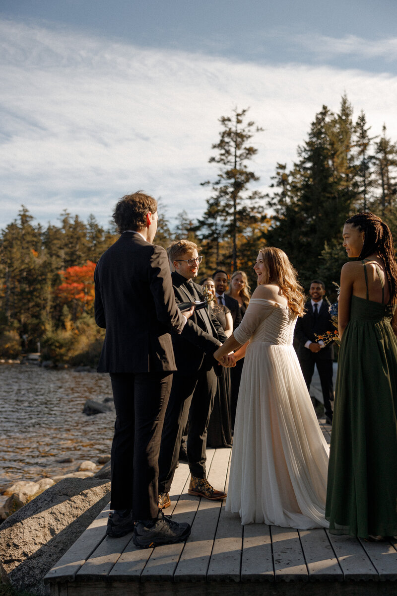 A person helping someone button up their wedding dress 