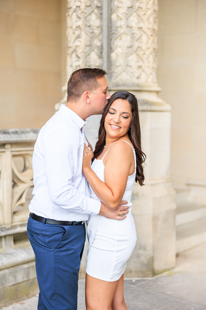 luxury couple with white dress posing closely in front of the columns at Biltmore Estate