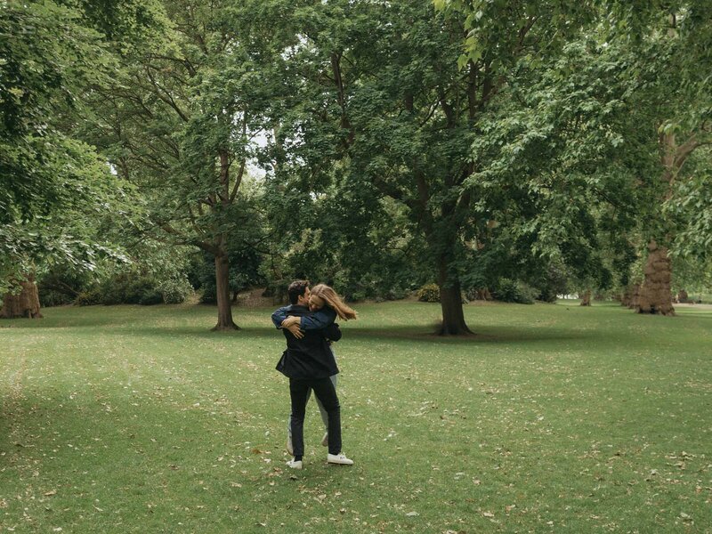 A couple embraces in a grassy field.