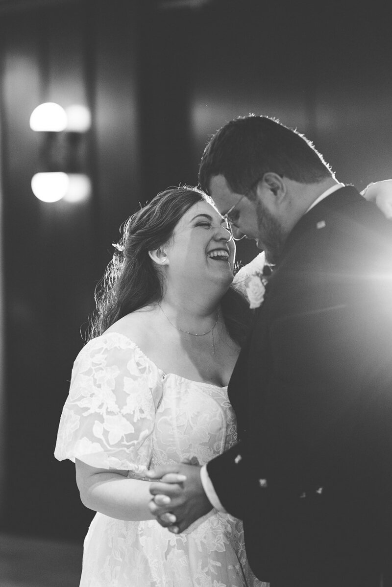 Black and white image of jewish bride and scottish groom dancing their first dancing smiling and laughing at one another