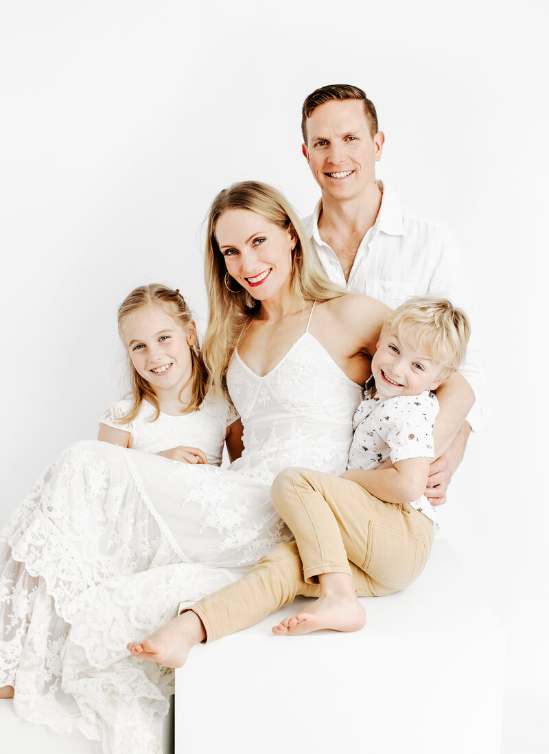 Family of 4 smiling for the camera for a family studio portrait by Lauren Vanier Photography