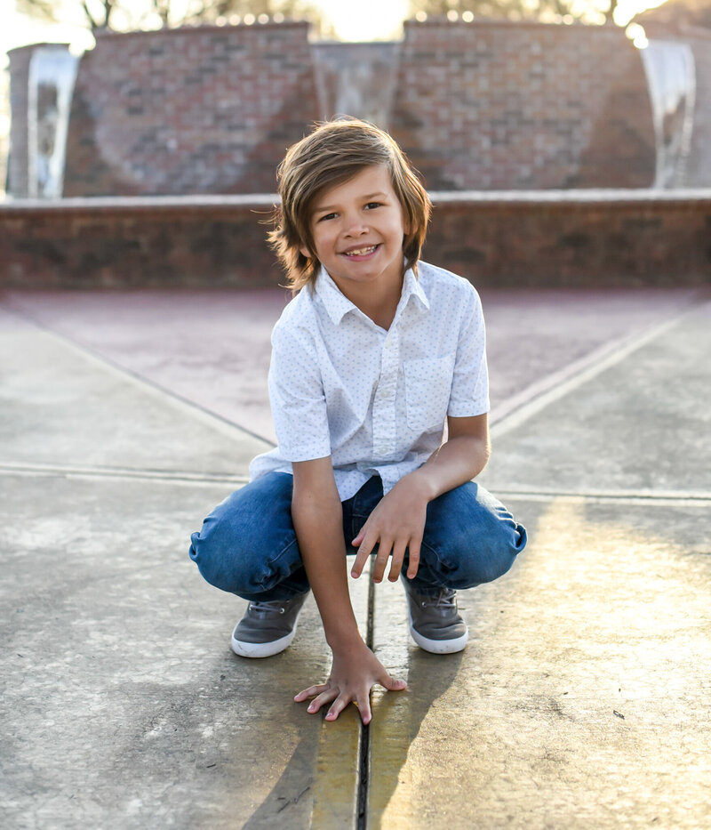 Young boy posing for his lifestyle photoshoot in front of a brick wall photographed by Millz Photography in Greenville, SC