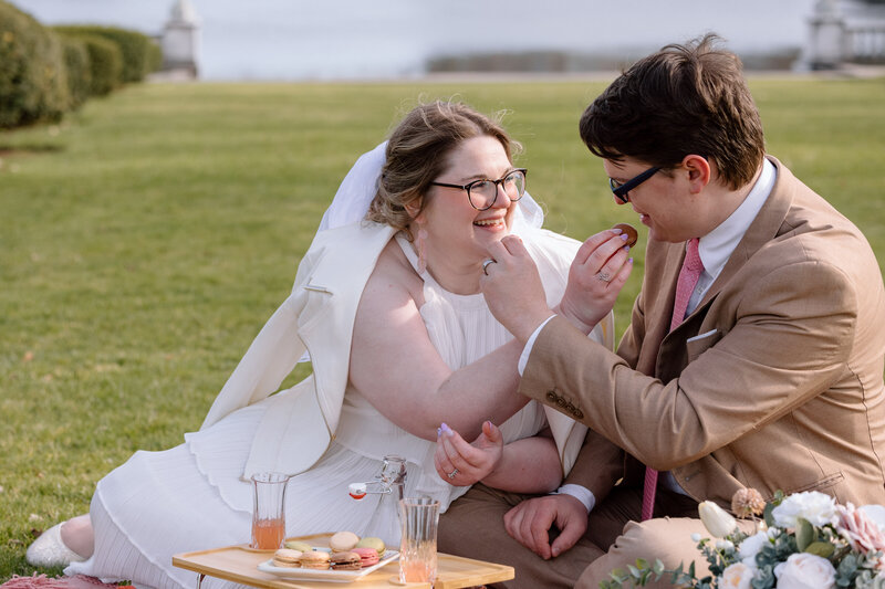 Bride and groom sitting down for a picnic at Wade Lagoon.