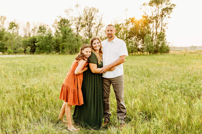 bride and groom standing with their daughter for family photo
