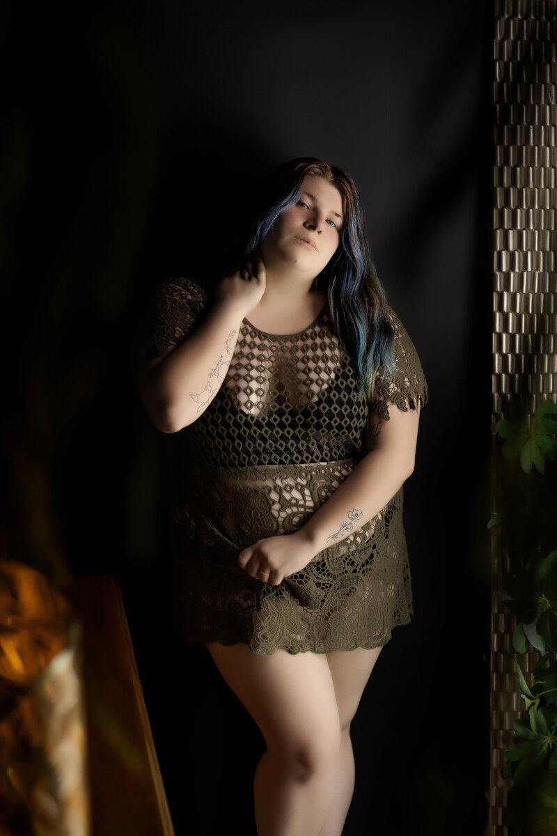 A stunning boudoir portrait of a confident woman in an olive lace dress, captured in a moody and intimate setting. Perfect for those searching for the best boudoir photographer in Cedar Rapids, Iowa, with competitive prices and exceptional reviews.