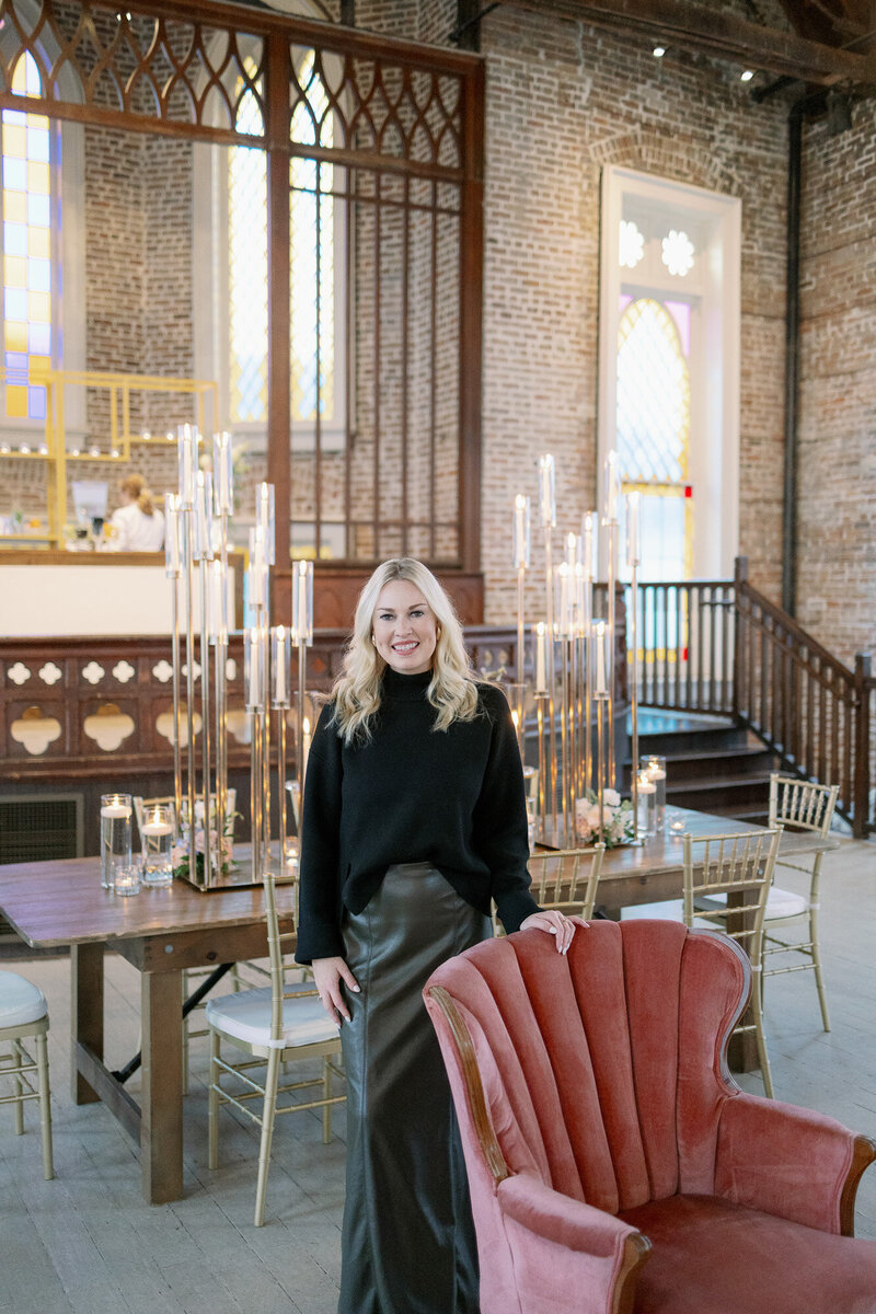 Natasha Kozlowski, luxury wedding planner in Austin and New Orleans, standing in front of red chair