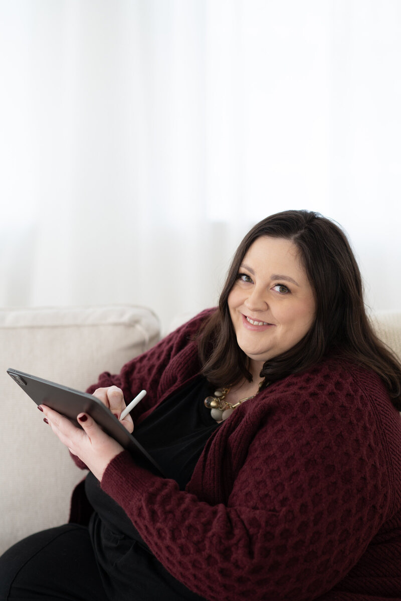 Sarah Shuttle smiling while working on a luxury brand design using iPad in her studio.