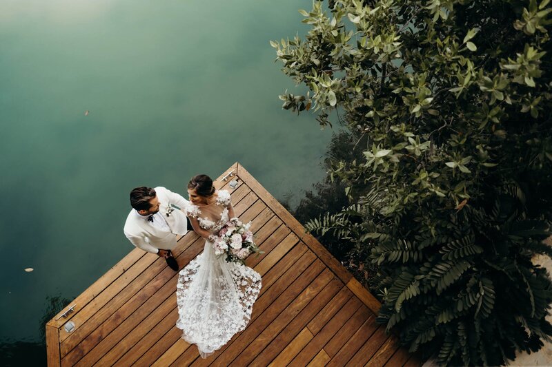 Rosewood Mayakoba wedding photo of the couple standing on a wooden dock next to a green pool of water
