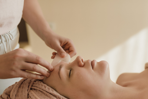 Closeup image of a woman lying down getting an IPL photofacial from an esthetician with baby pink gloves