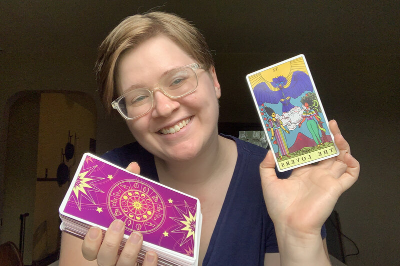 A Virginia elopement smiles widely as she holds her tarot deck in one hand and The Lovers card in the other.