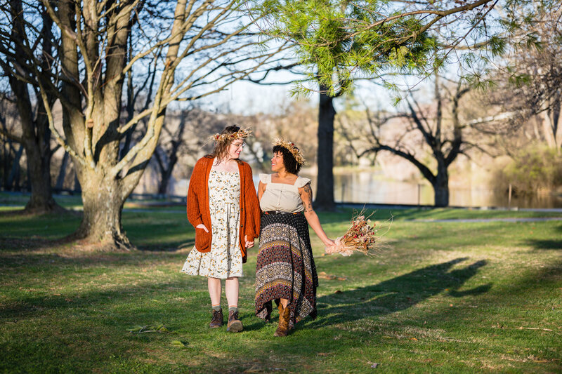 An LGBTQ+ couple walks hand-in-hand and smile at one another on their elopement wedding day.