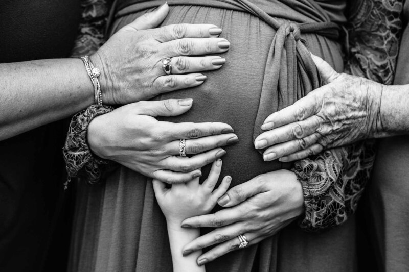 Multi-generational hands close up pressed against pregnant belly